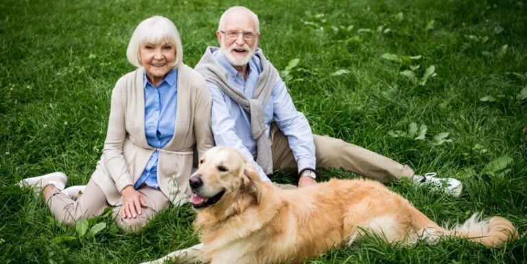 Senior Couple with Golden Retriever on Grass at Memory Care Facility