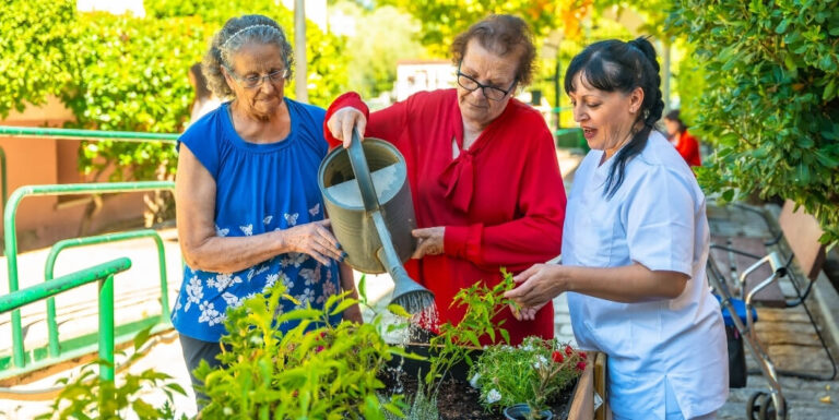 Nursing Staff Assisting Elderly Residents with Outdoor Gardening at an Assisted Living Facility